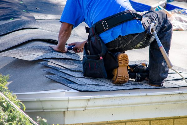 A worker replaces tiles on the roof of a home